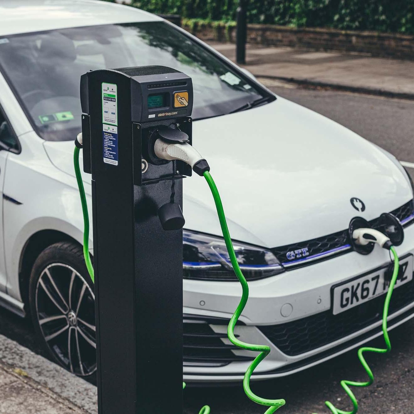 London/UK-30/07/18: white Volkswagen Golf GTE cars charging at a charging point on a street in London. The Golf GTE is a plug-in hybrid version of the Golf hatchback